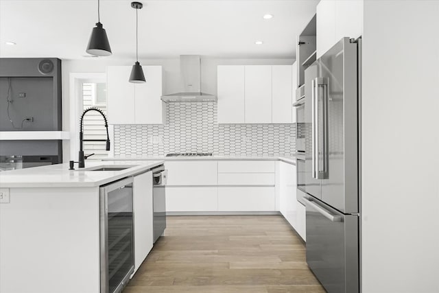 kitchen with appliances with stainless steel finishes, wall chimney range hood, modern cabinets, and recessed lighting