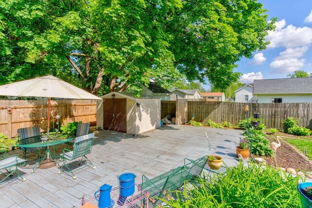 606 E Houghton St, Tuscola, IL 61953 - view of patio featuring a storage unit, an outdoor structure, a wooden deck, a fenced backyard, and outdoor dining area