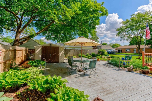 606 E Houghton St, Tuscola, IL 61953 - wooden terrace featuring a storage unit, an outbuilding, a fenced backyard, and outdoor dining area