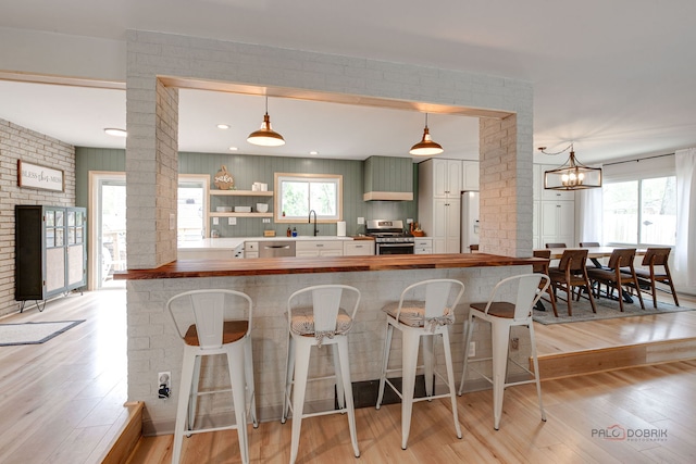 5045 S Rd, Gurnee, IL 60031 - kitchen featuring stainless steel appliances, butcher block counters, decorative columns, light wood-type flooring, and a sink