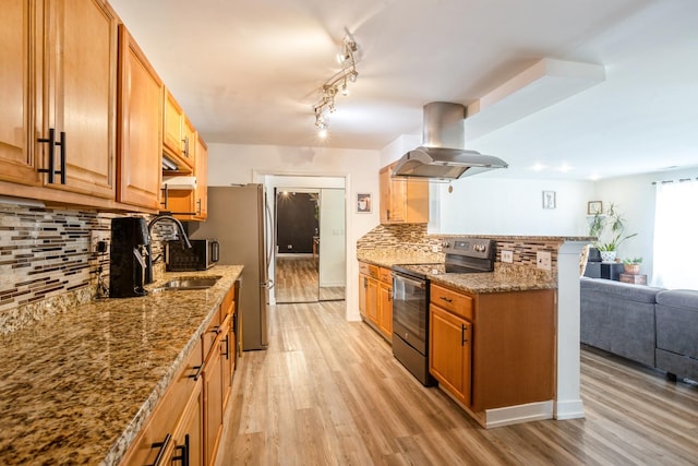 kitchen featuring range with electric cooktop, island range hood, decorative backsplash, a sink, and light wood-style flooring