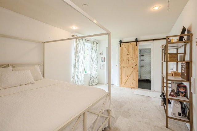 bedroom with a barn door and light carpet