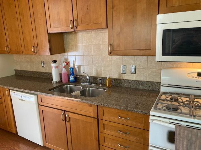 950 Arlon Rd, Aurora, IL 60506 - kitchen with white appliances, a sink, brown cabinets, tasteful backsplash, and dark stone countertops