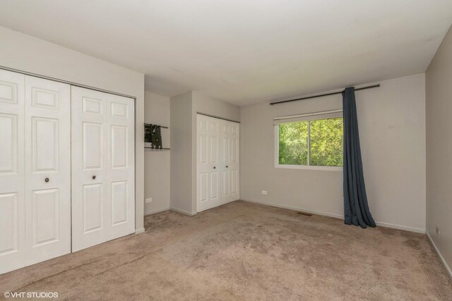 618 Hampton Cir, Elgin, IL 60120 - unfurnished bedroom with carpet, baseboards, and two closets