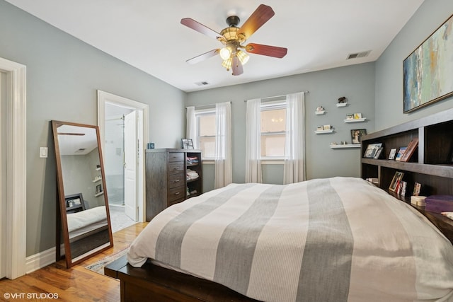 bedroom with wood finished floors, ensuite bathroom, ceiling fan, and baseboards