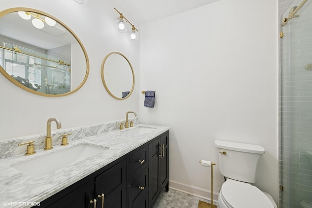 bathroom featuring toilet, tiled shower, baseboards, and double vanity
