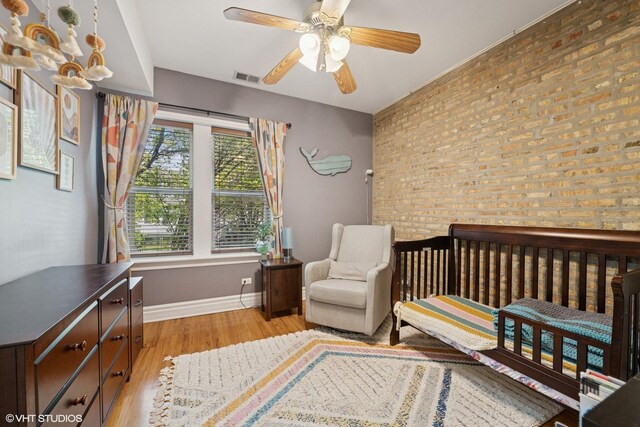 3515 W Medill Ave Unit 1W, Chicago, IL 60647 - bedroom with baseboards, light wood-style floors, brick wall, and ceiling fan