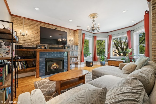 living room featuring a chandelier, a fireplace, wood finished floors, ornamental molding, and recessed lighting