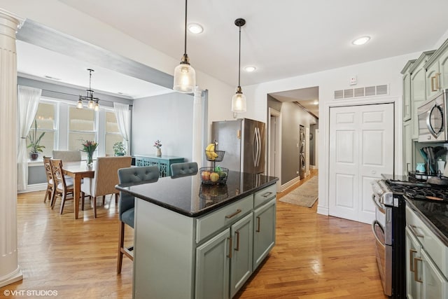 kitchen featuring appliances with stainless steel finishes, light wood-style floors, a kitchen island, recessed lighting, and hanging light fixtures