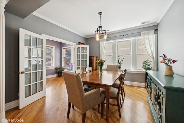 dining area with baseboards, ornamental molding, a chandelier, and light wood finished floors