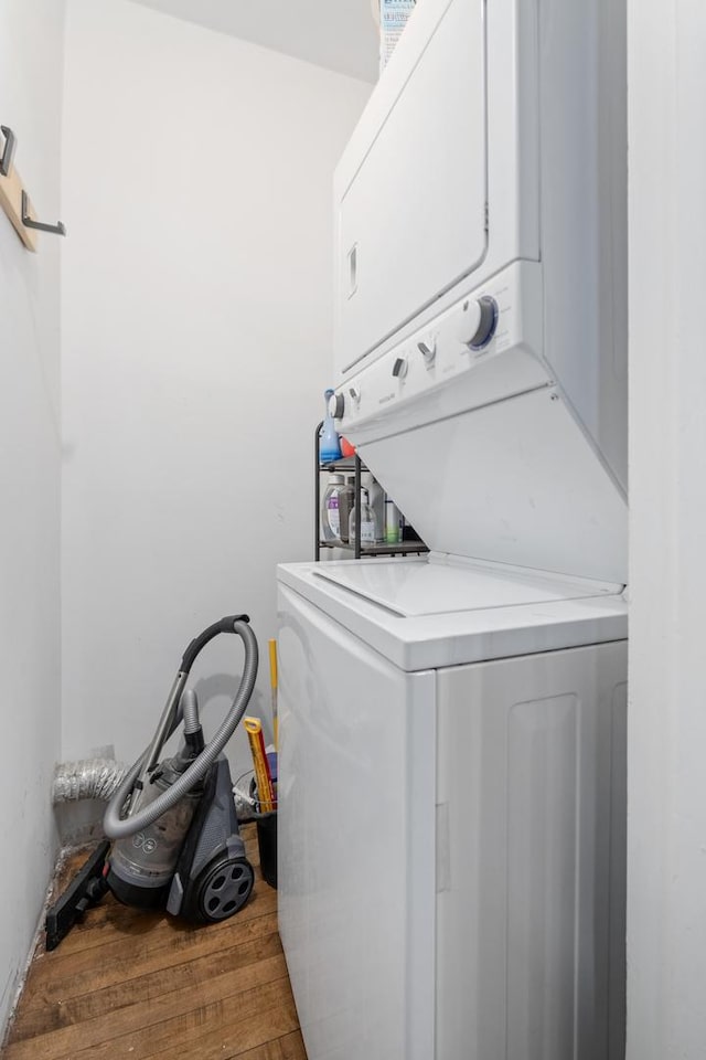 clothes washing area featuring stacked washer / dryer and wood finished floors