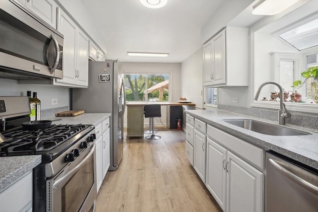 735 Lamon Ave, Wilmette, IL 60091 - kitchen featuring appliances with stainless steel finishes, a sink, white cabinetry, light wood finished floors, and light countertops