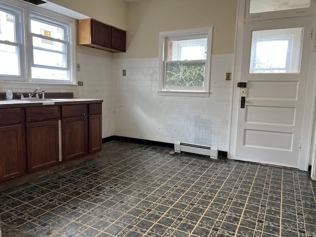3423 N Tripp Ave, Chicago, IL 60641 - kitchen featuring tile walls, a sink, baseboard heating, light countertops, and wainscoting