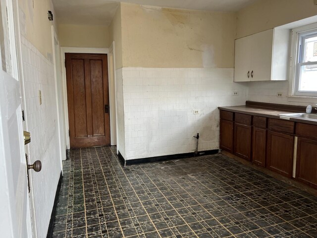 3423 N Tripp Ave, Chicago, IL 60641 - kitchen with tile walls, dark floors, a sink, and a wainscoted wall