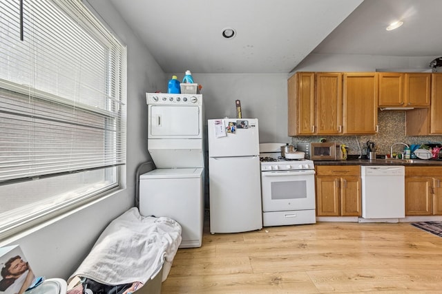 2443 N Marshfield Ave, Chicago, IL 60614 - kitchen with white appliances, stacked washing machine and dryer, a sink, light wood finished floors, and dark countertops