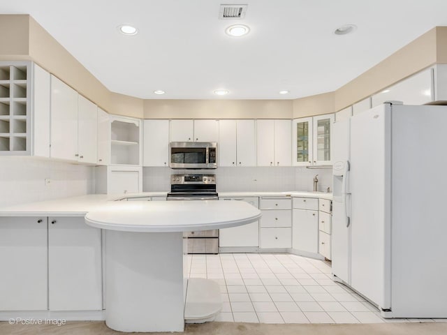 1409 Burr Oak Rd Unit 109A, Hinsdale, IL 60521 - kitchen featuring appliances with stainless steel finishes, a peninsula, decorative backsplash, light countertops, and glass insert cabinets