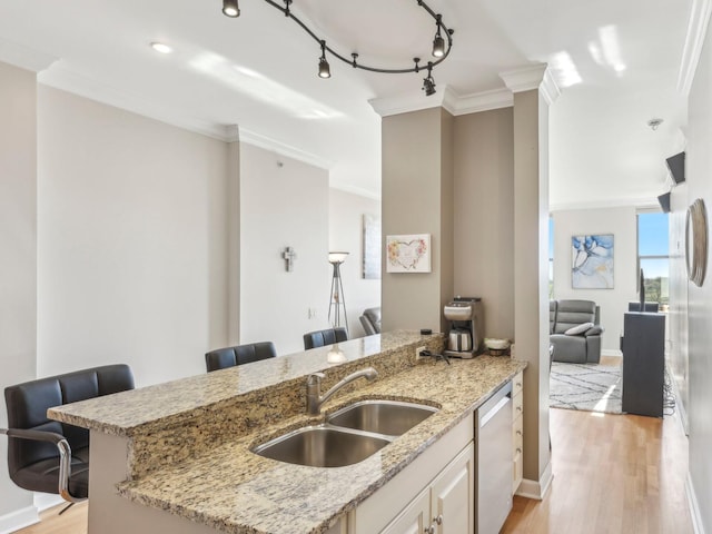 kitchen with a sink, dishwasher, ornamental molding, light stone countertops, and light wood-type flooring