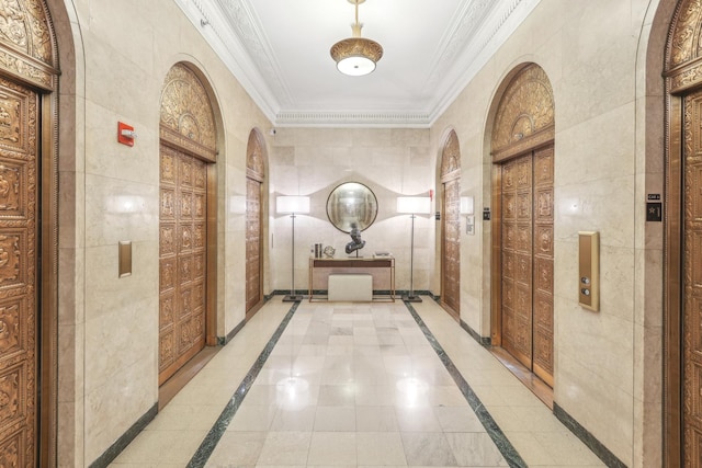 hall featuring inlaid floor details, tile walls, crown molding, and arched walkways