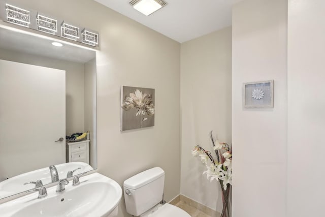 bathroom with a sink, toilet, and baseboards