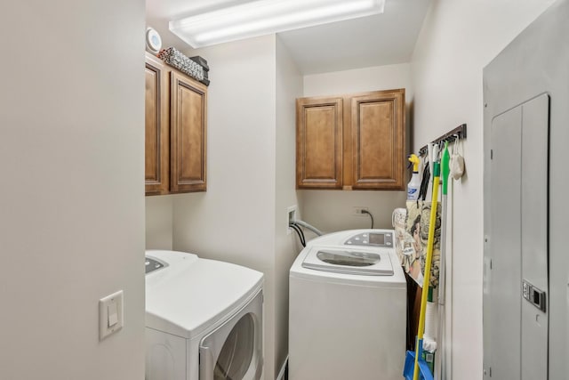 clothes washing area with separate washer and dryer and cabinet space