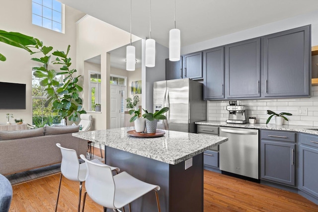 698 S Jade Ln Unit 698, Round Lake, IL 60073 - kitchen featuring stainless steel appliances, a kitchen breakfast bar, tasteful backsplash, light stone countertops, and wood finished floors