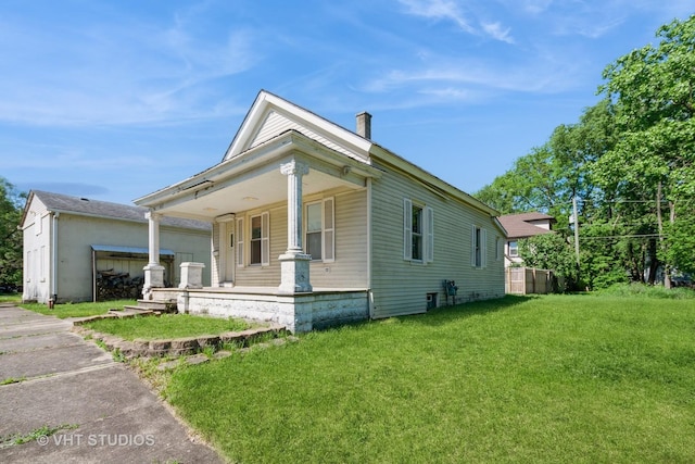 view of side of home featuring covered porch, a yard, and a chimney