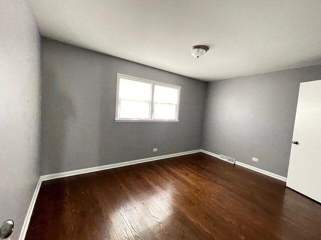 spare room featuring dark wood finished floors and baseboards