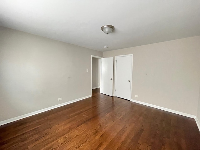 unfurnished bedroom with dark wood finished floors and baseboards