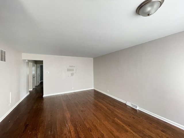 empty room featuring dark wood-type flooring and baseboards
