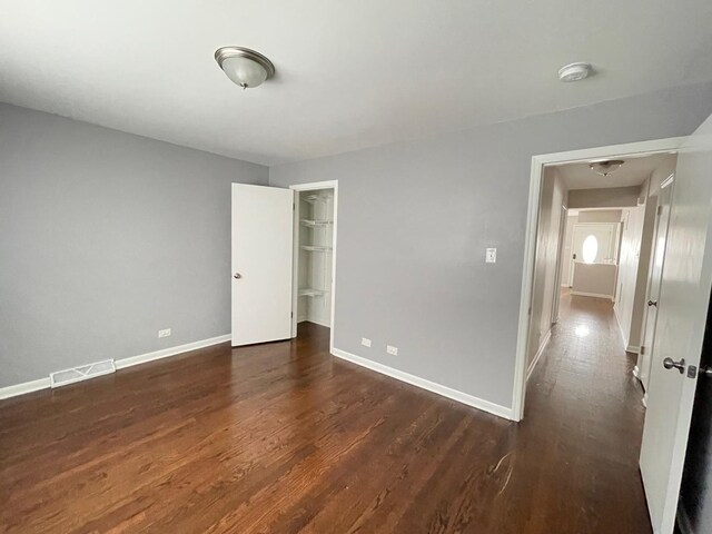 unfurnished bedroom with dark wood-type flooring, baseboards, and a closet