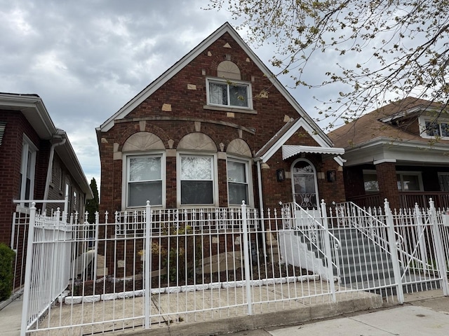 english style home with brick siding and a fenced front yard