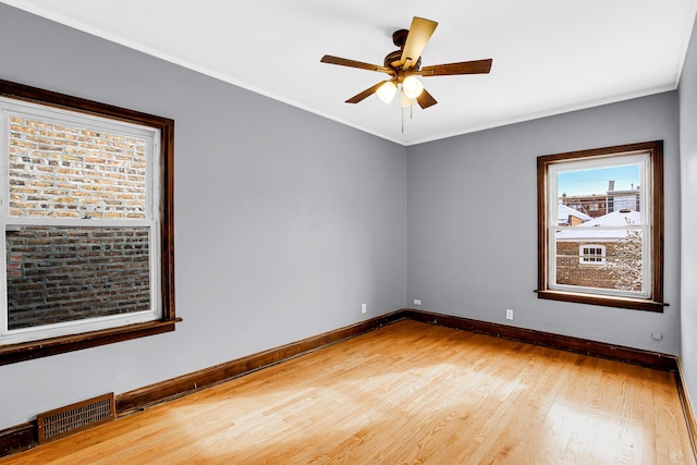 spare room featuring baseboards, light wood-style flooring, ceiling fan, and ornamental molding