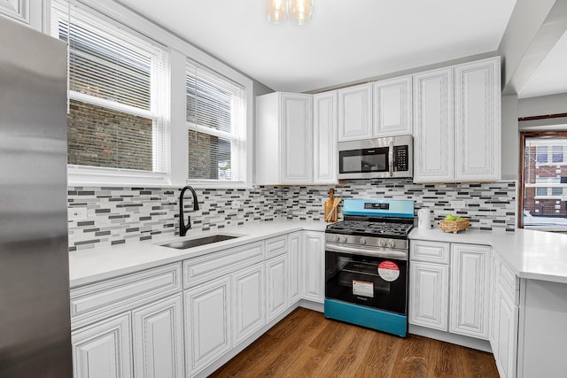 kitchen featuring appliances with stainless steel finishes, a sink, dark wood-style floors, light countertops, and tasteful backsplash