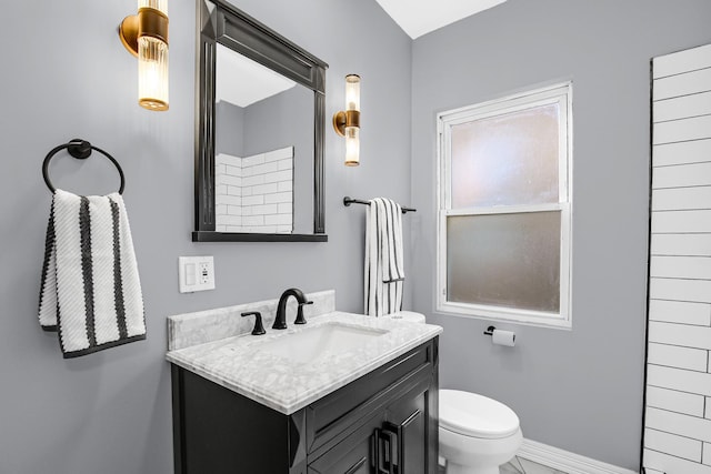 bathroom featuring toilet, vanity, and baseboards