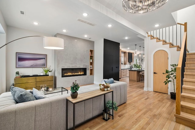 3104 N Sacramento Ave, Chicago, IL 60618 - living area featuring stairway, light wood-style floors, a fireplace, a chandelier, and recessed lighting