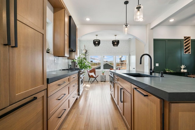 3104 N Sacramento Ave, Chicago, IL 60618 - kitchen featuring a sink, arched walkways, dark countertops, stainless steel range, and pendant lighting