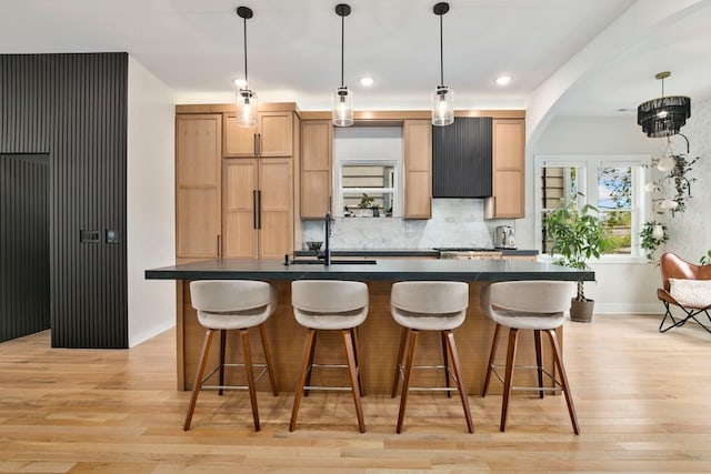 3104 N Sacramento Ave, Chicago, IL 60618 - kitchen featuring dark countertops, a center island with sink, a sink, light wood-style floors, and recessed lighting