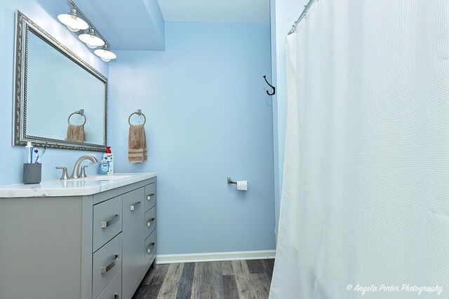 full bathroom with wood finished floors, vanity, and baseboards