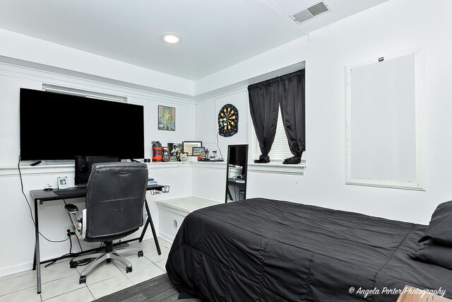 bedroom with light tile patterned flooring and an office area