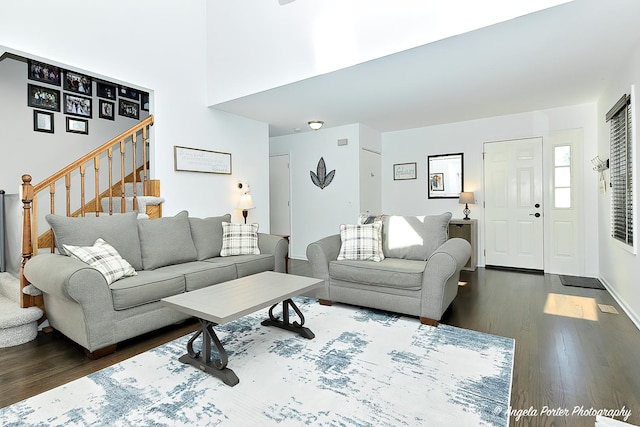 living room featuring dark wood-type flooring and stairs