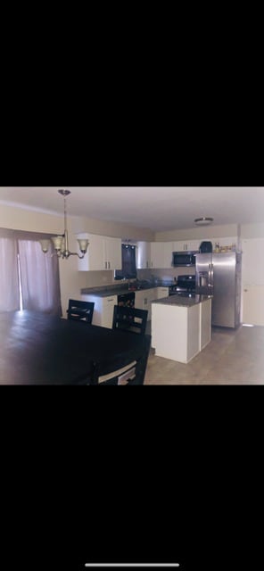kitchen with appliances with stainless steel finishes, white cabinets, a kitchen island, and a chandelier