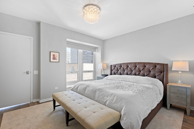 bedroom with wood finished floors, a chandelier, and baseboards