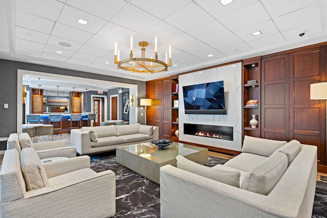 living area with a chandelier, a high end fireplace, a paneled ceiling, recessed lighting, and crown molding