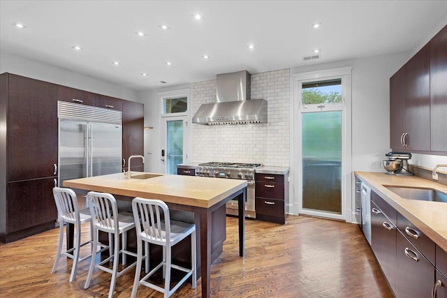 1313 N Wood St Unit 2, Chicago, IL 60622 - kitchen with wall chimney range hood, high end appliances, a sink, light wood-style flooring, and recessed lighting
