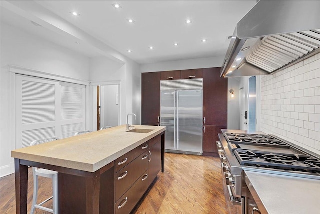 1313 N Wood St Unit 2, Chicago, IL 60622 - kitchen with stainless steel built in fridge, range hood, a sink, cooktop, and dark brown cabinetry