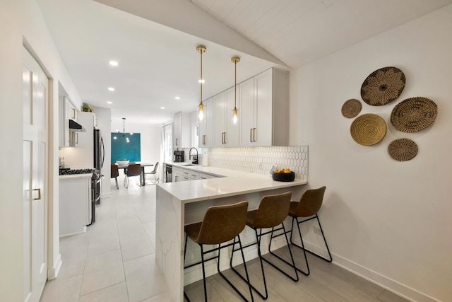 kitchen featuring decorative backsplash, a kitchen breakfast bar, light countertops, a peninsula, and white cabinets