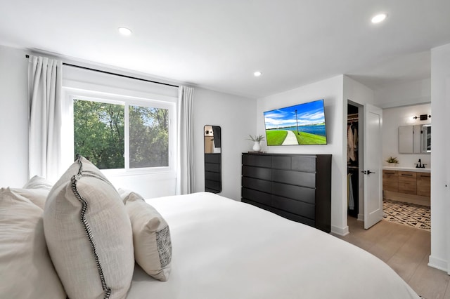 bedroom featuring recessed lighting, light wood finished floors, and ensuite bath