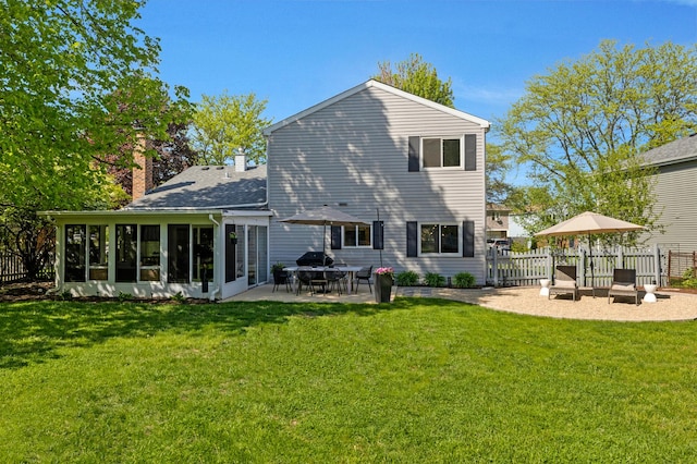 rear view of property featuring a sunroom, a patio, and a chimney