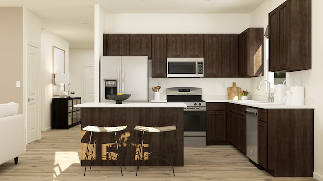 kitchen featuring appliances with stainless steel finishes, dark brown cabinets, light wood finished floors, a kitchen breakfast bar, and light countertops