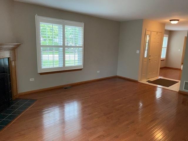20827 W Torrey Pines Ln, Plainfield, IL 60544 - unfurnished living room featuring wood-type flooring, a tiled fireplace, plenty of natural light, and baseboards